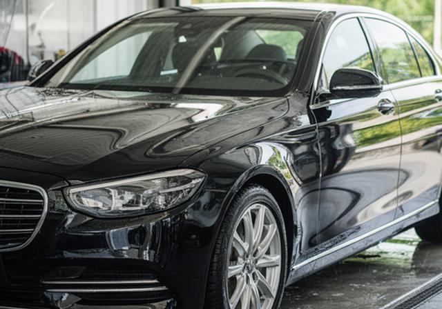 Coche negro con acabado brillante tras encerado profesional en el centro de lavado de Torrejón, reflejando el entorno con nitidez